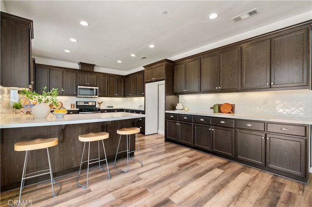 kitchen featuring dark brown cabinets, stainless steel appliances, recessed lighting, a peninsula, and visible vents