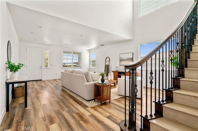 living area featuring stairs, baseboards, wood finished floors, and a high ceiling