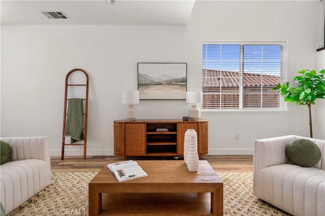 living room featuring baseboards, visible vents, and light wood-style flooring