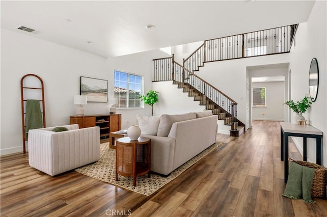 living room featuring baseboards, stairs, wood finished floors, and visible vents