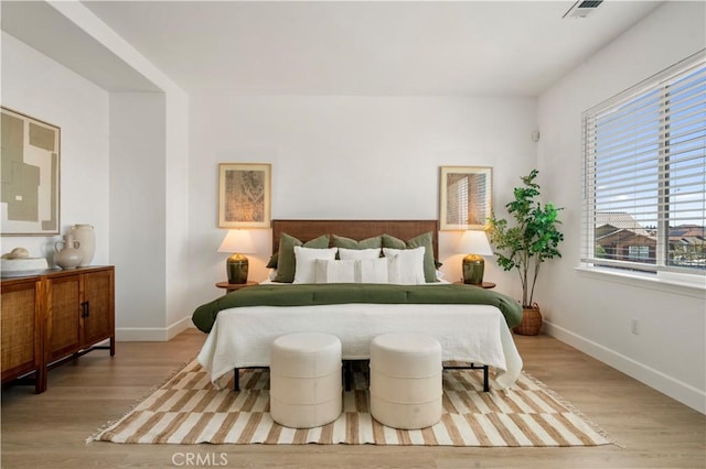 bedroom with light wood-style floors, baseboards, and multiple windows