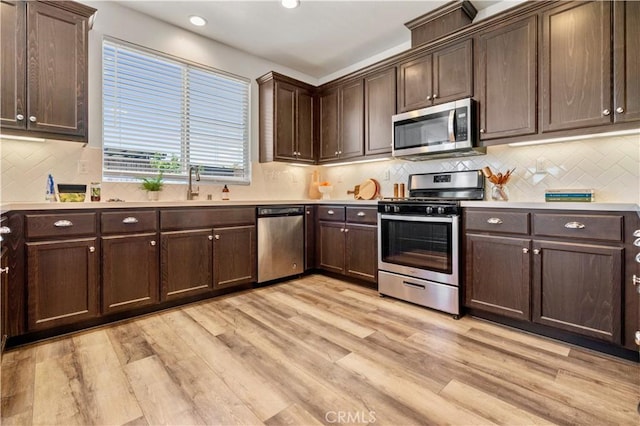 kitchen featuring light countertops, dark brown cabinetry, appliances with stainless steel finishes, and light wood-type flooring