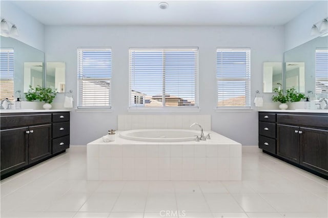 full bath featuring tile patterned flooring, a bath, and two vanities