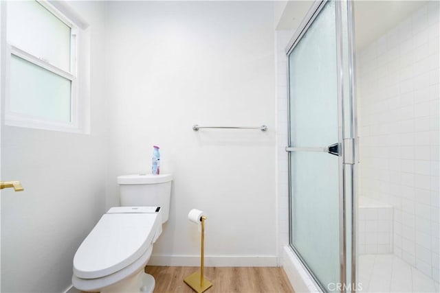full bathroom featuring toilet, baseboards, tiled shower, and wood finished floors