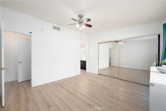 empty room featuring visible vents, ceiling fan, and wood finished floors