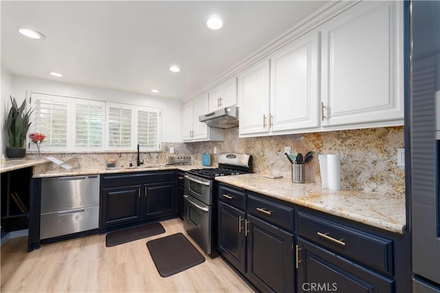 kitchen featuring a sink, stainless steel appliances, white cabinetry, backsplash, and under cabinet range hood