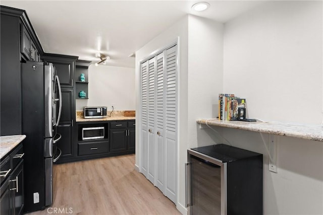4321 Matilija Ave Unit 9, Sherman Oaks, CA 91423 - kitchen featuring appliances with stainless steel finishes, light wood finished floors, dark cabinets, light stone countertops, and open shelves
