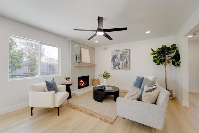 living area with light wood-style floors, recessed lighting, baseboards, and a large fireplace