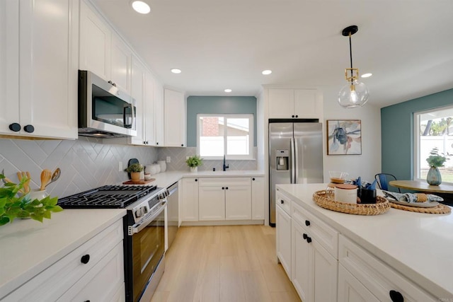 kitchen with white cabinetry, appliances with stainless steel finishes, a wealth of natural light, and light wood finished floors
