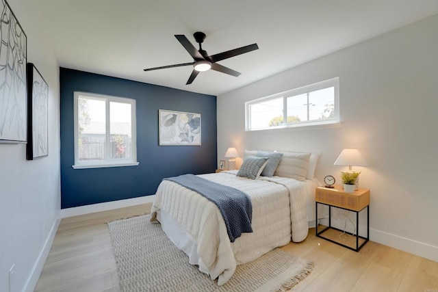 bedroom with light wood-style floors, a ceiling fan, baseboards, and multiple windows