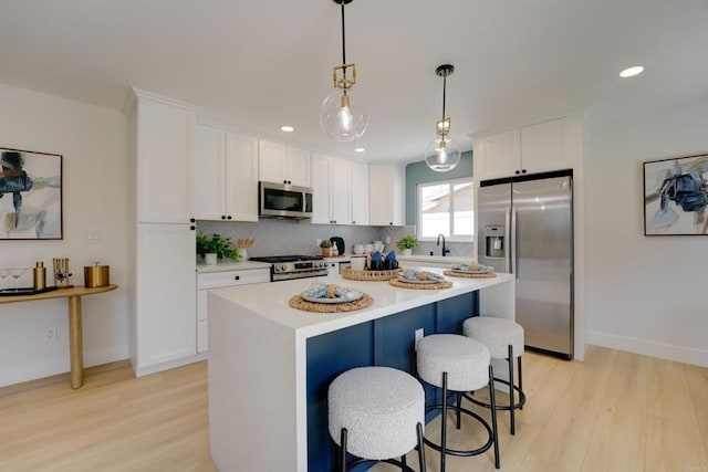 kitchen featuring light wood-type flooring, white cabinetry, tasteful backsplash, and stainless steel appliances