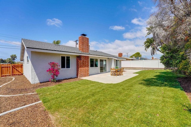 rear view of house featuring a lawn, a patio, a chimney, and a fenced backyard