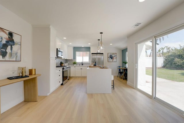 kitchen with white cabinetry, appliances with stainless steel finishes, a breakfast bar area, and light wood finished floors