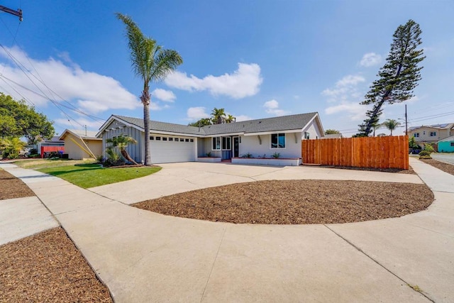 ranch-style home with an attached garage, board and batten siding, fence, and driveway