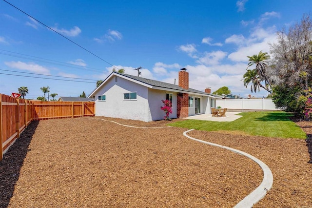 back of property with a chimney, a lawn, a patio area, a fenced backyard, and stucco siding