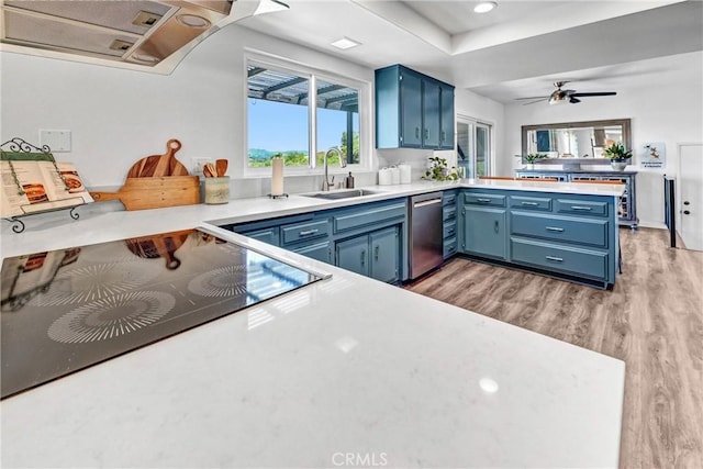 kitchen featuring a peninsula, light wood-style floors, a sink, dishwasher, and blue cabinetry