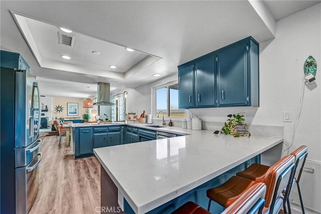 1864 Winterwarm Dr, Fallbrook, CA 92028 - kitchen with stainless steel fridge, a peninsula, blue cabinetry, a sink, and light wood-style flooring