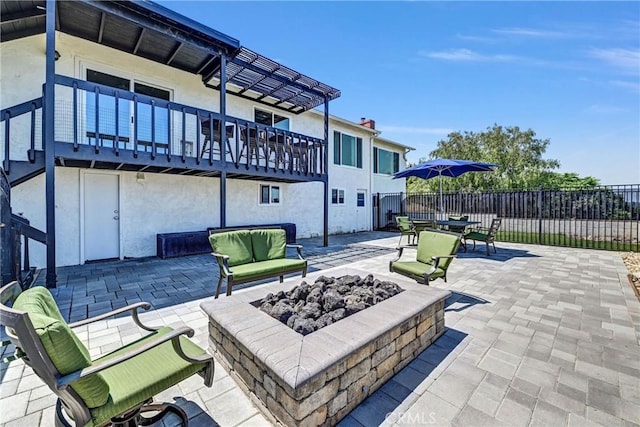 view of patio featuring fence, an outdoor living space with a fire pit, and a balcony