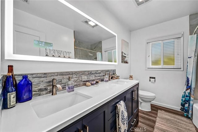bathroom with a sink, curtained shower, wood finished floors, and visible vents