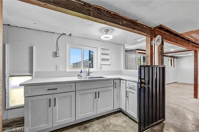 kitchen featuring light countertops, a sink, and unfinished concrete flooring