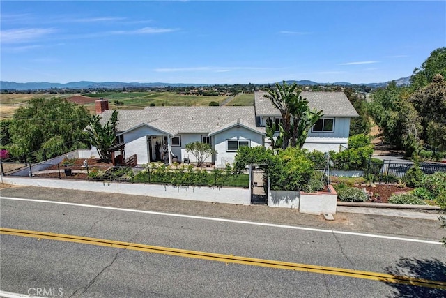 ranch-style home featuring a mountain view and a fenced front yard