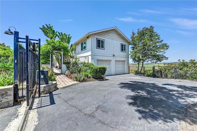 view of property exterior with fence, board and batten siding, aphalt driveway, and a garage