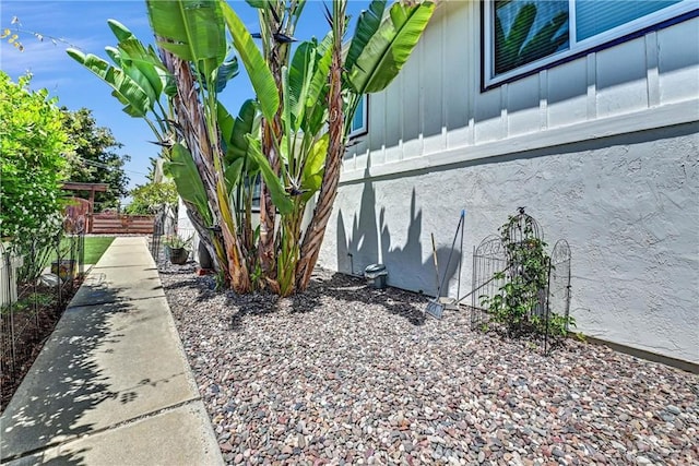 view of side of property with stucco siding, board and batten siding, and fence