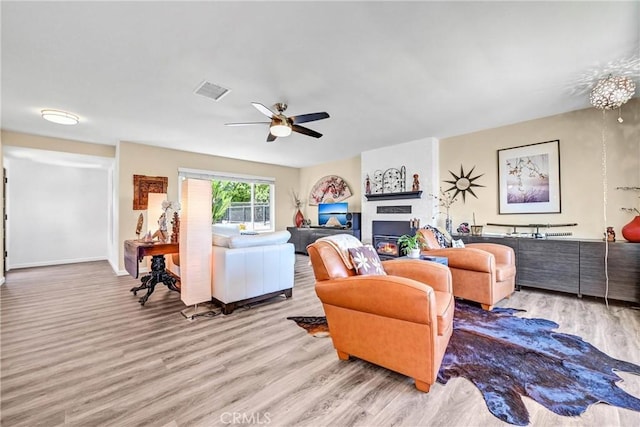 living area with a ceiling fan, baseboards, visible vents, and wood finished floors