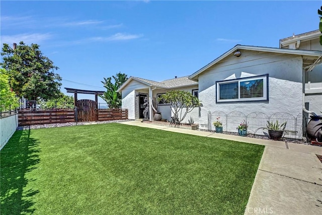 view of front facade featuring fence private yard, a gate, stucco siding, and a front yard