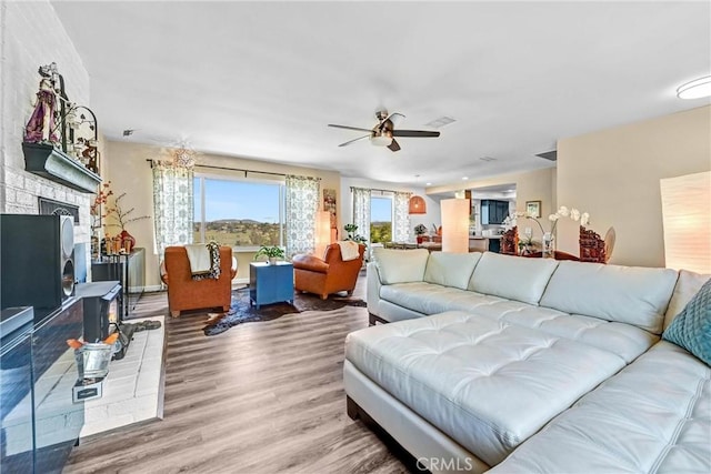 living room featuring visible vents, a ceiling fan, wood finished floors, and a fireplace