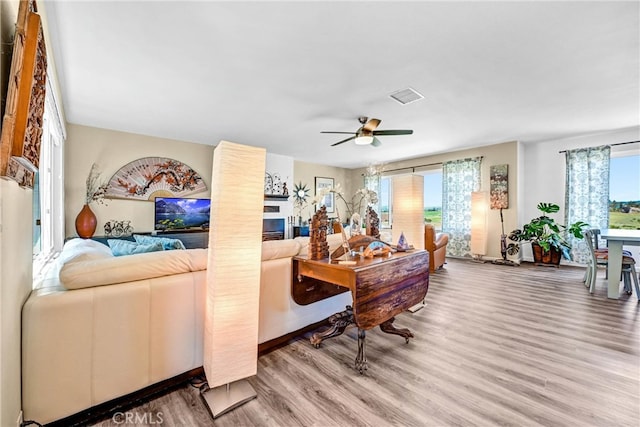 living area featuring ceiling fan, visible vents, and wood finished floors