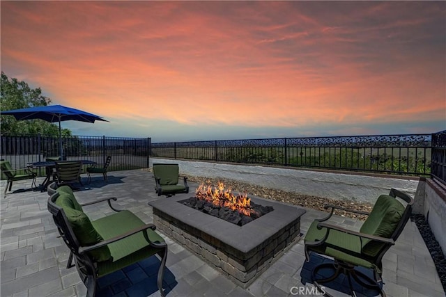 patio terrace at dusk with a fenced backyard and an outdoor fire pit