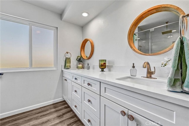 full bathroom with a sink, double vanity, a shower stall, a wealth of natural light, and wood finished floors