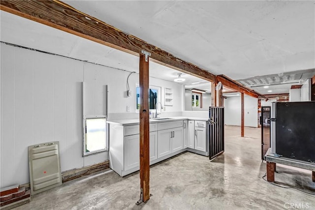 kitchen featuring light countertops, concrete flooring, and a sink