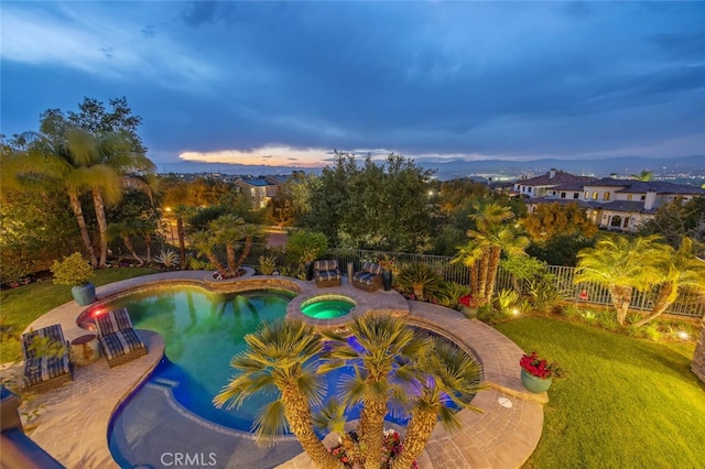 view of swimming pool featuring a pool with connected hot tub and fence