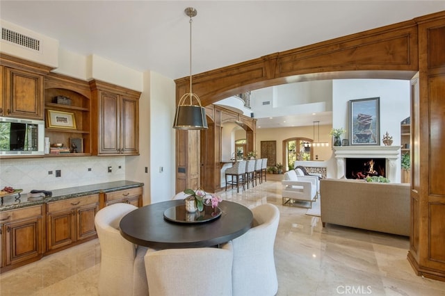 kitchen with visible vents, decorative backsplash, open shelves, stainless steel microwave, and brown cabinets