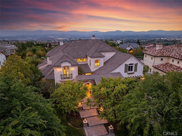 view of front of house with a mountain view, stucco siding, a balcony, and a chimney