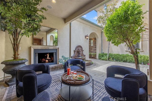 view of patio with a warm lit fireplace