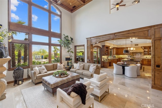 living room with a high ceiling, a ceiling fan, and marble finish floor