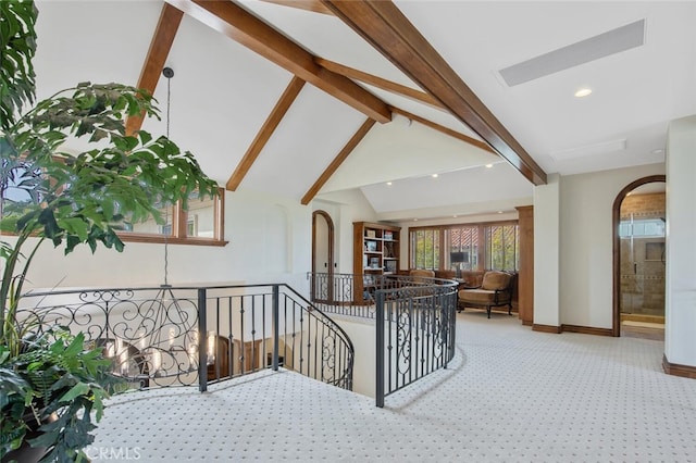 interior space with visible vents, arched walkways, baseboards, carpet floors, and lofted ceiling with beams
