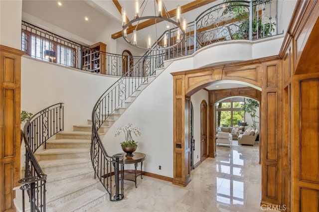 entryway with arched walkways, an inviting chandelier, marble finish floor, and a towering ceiling