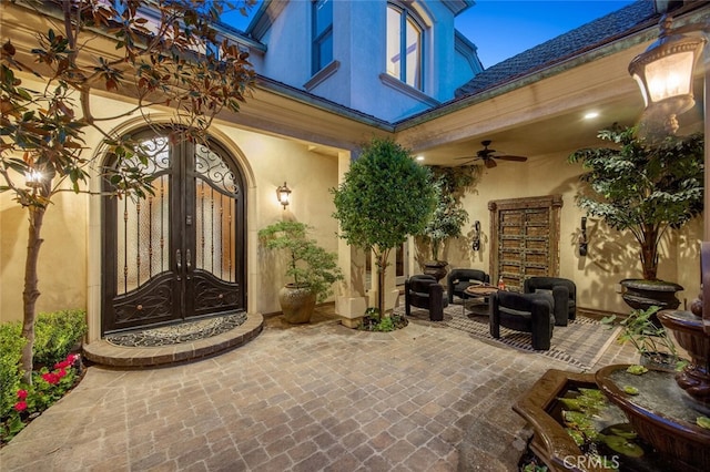 view of exterior entry with french doors, a patio, a ceiling fan, and stucco siding