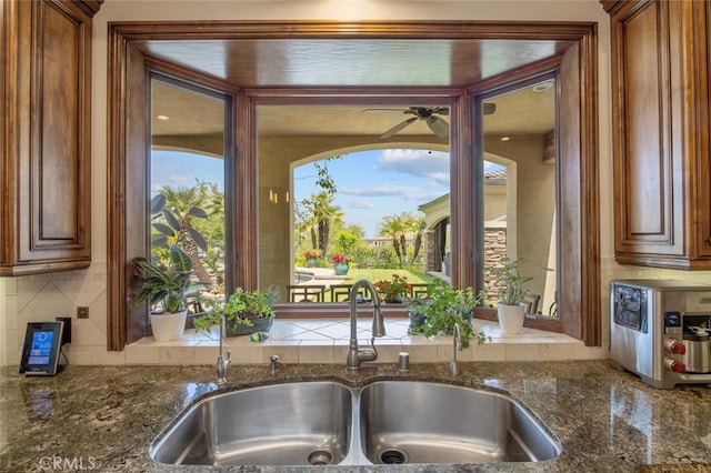 kitchen with a sink, decorative backsplash, ceiling fan, and brown cabinets
