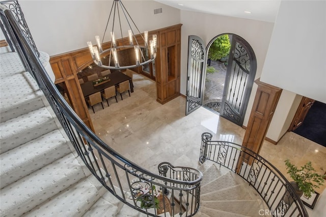 foyer entrance featuring stairway, a notable chandelier, vaulted ceiling, and visible vents