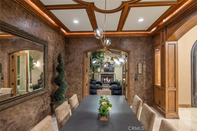 dining room featuring crown molding, coffered ceiling, and a premium fireplace