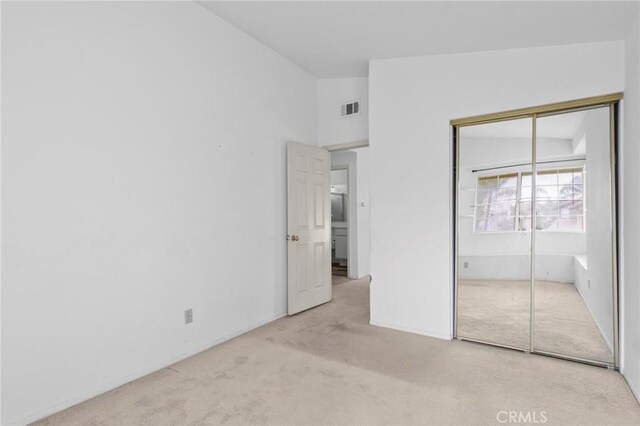 unfurnished bedroom with a closet, carpet flooring, lofted ceiling, and visible vents