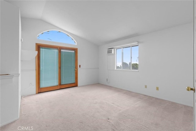 empty room with carpet floors, a wall unit AC, and lofted ceiling