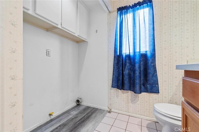 laundry room featuring baseboards, wallpapered walls, and light wood finished floors