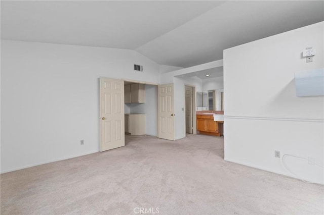 interior space featuring visible vents, baseboards, vaulted ceiling, and light carpet