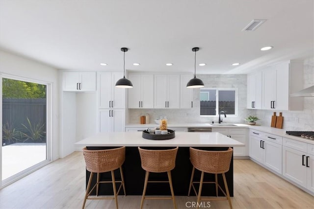 24531 Bunbury Dr, Lake Forest, CA 92630 - kitchen featuring a sink, light countertops, decorative backsplash, a kitchen island, and visible vents